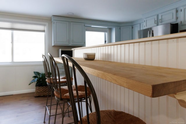 bar featuring freestanding refrigerator, baseboards, and wood finished floors