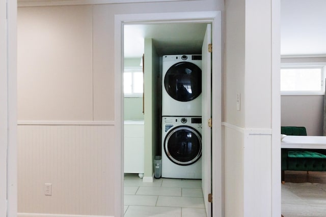 laundry room with stacked washer and dryer, laundry area, a wealth of natural light, and a wainscoted wall