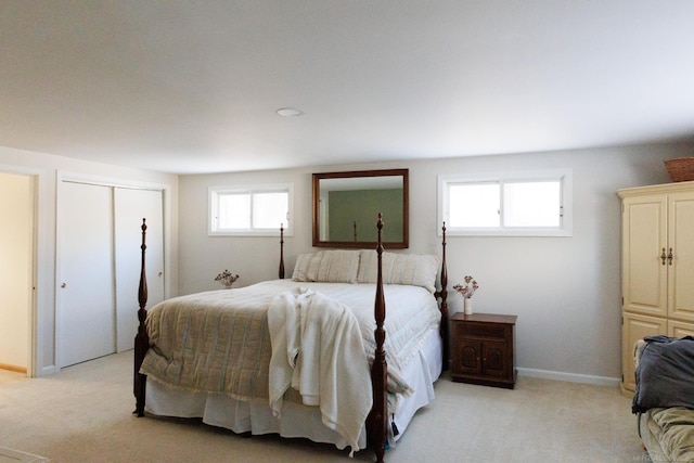 bedroom with a closet, light carpet, and baseboards