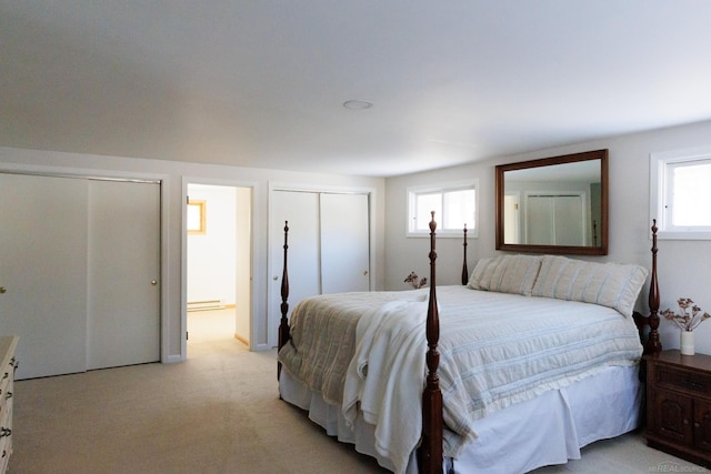 bedroom with multiple closets, light colored carpet, multiple windows, and connected bathroom