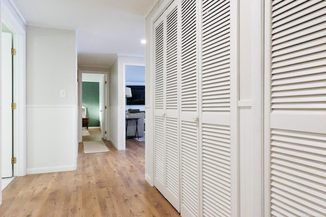 corridor featuring light wood finished floors and a wainscoted wall