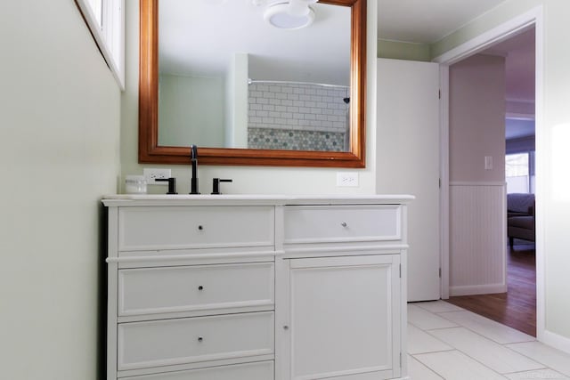 bathroom featuring a wainscoted wall, tile patterned flooring, walk in shower, and vanity