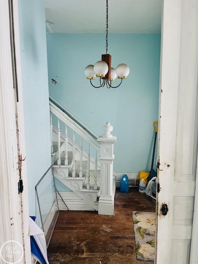 interior space featuring stairway, wood-type flooring, and an inviting chandelier