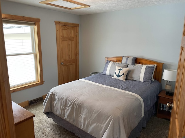 bedroom featuring a textured ceiling, carpet, visible vents, and baseboards