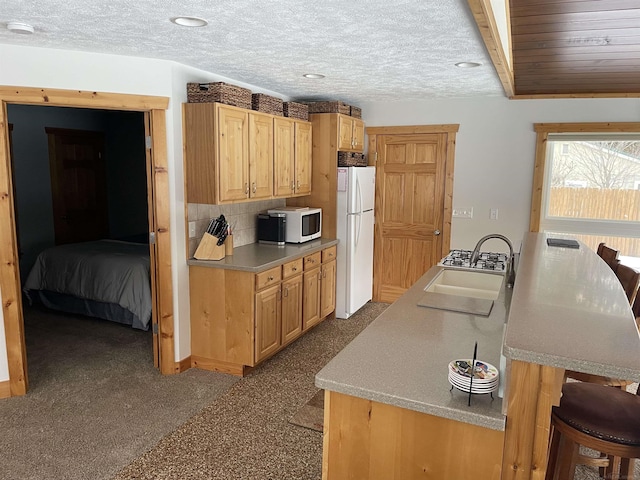 kitchen featuring white appliances, light countertops, backsplash, and light brown cabinetry