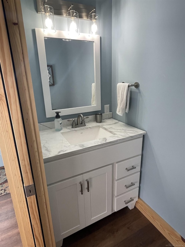 bathroom with baseboards, wood finished floors, and vanity