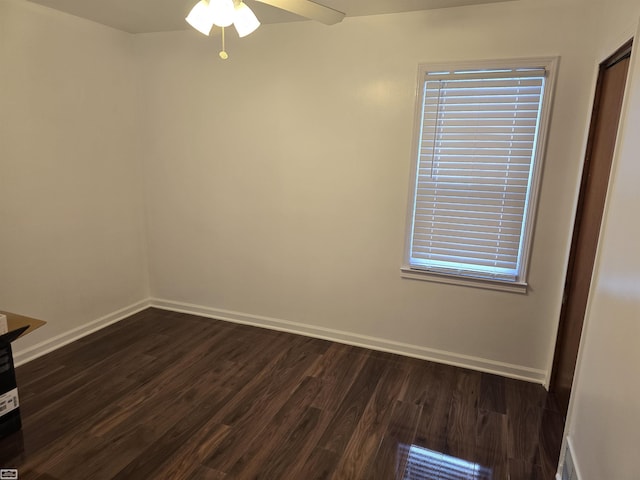 empty room with ceiling fan, dark wood finished floors, and baseboards