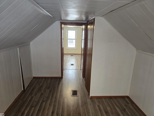 additional living space with lofted ceiling, visible vents, and dark wood finished floors