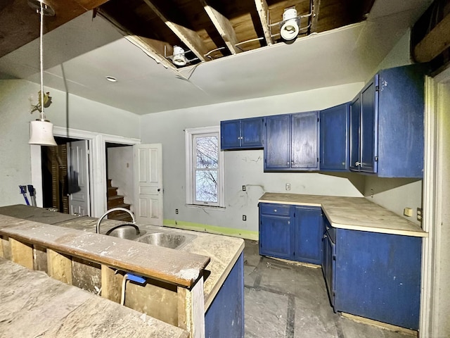 kitchen with blue cabinets, light countertops, a sink, and decorative light fixtures