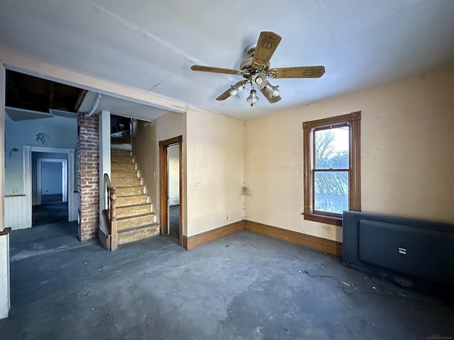 empty room with ceiling fan, concrete floors, stairway, and baseboards