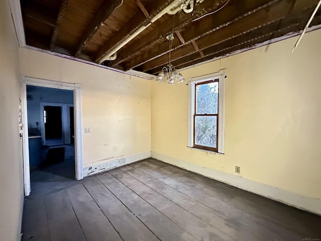 unfurnished room featuring wood finished floors and an inviting chandelier