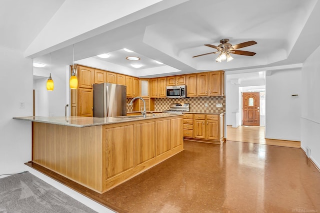 kitchen featuring tasteful backsplash, decorative light fixtures, a peninsula, a tray ceiling, and stainless steel appliances