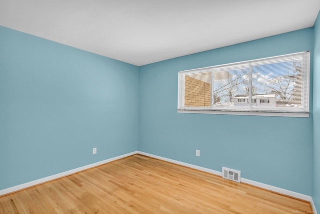 unfurnished room with wood finished floors, visible vents, and baseboards