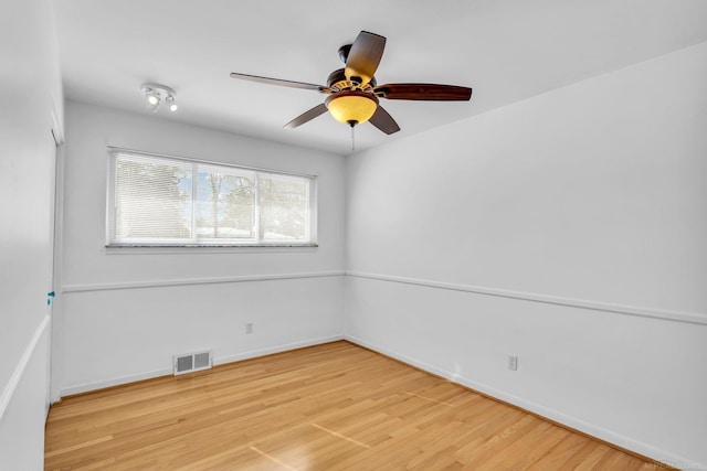 empty room featuring baseboards, visible vents, ceiling fan, and wood finished floors