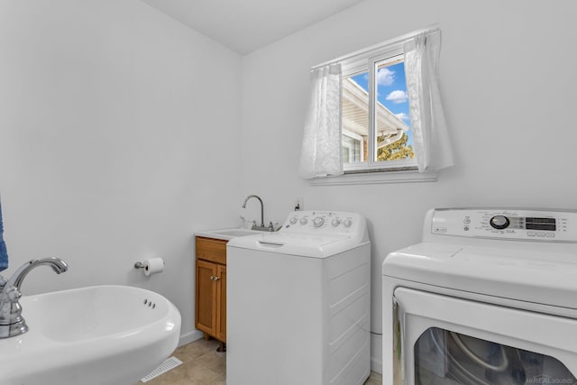 laundry area featuring laundry area, light tile patterned floors, washer and clothes dryer, and a sink