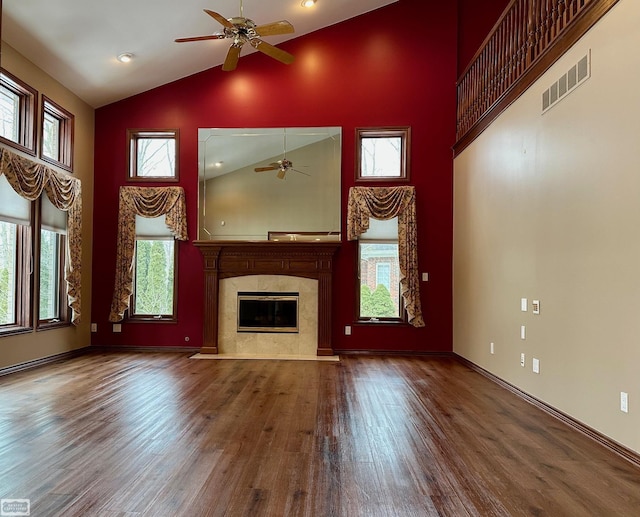 unfurnished living room featuring high vaulted ceiling, a fireplace, wood finished floors, visible vents, and baseboards