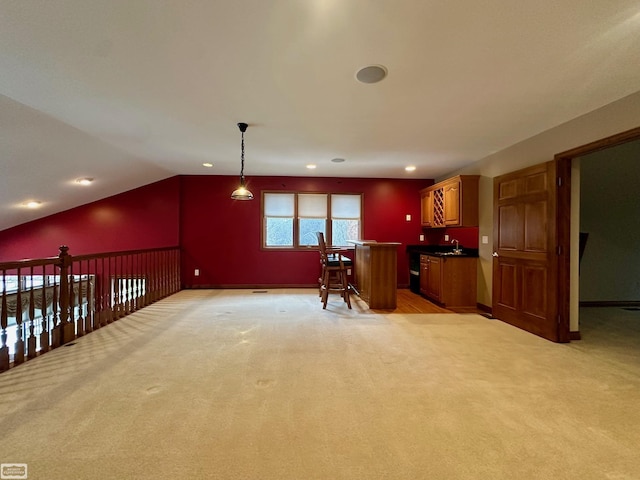 interior space featuring brown cabinetry, dark countertops, open floor plan, vaulted ceiling, and pendant lighting