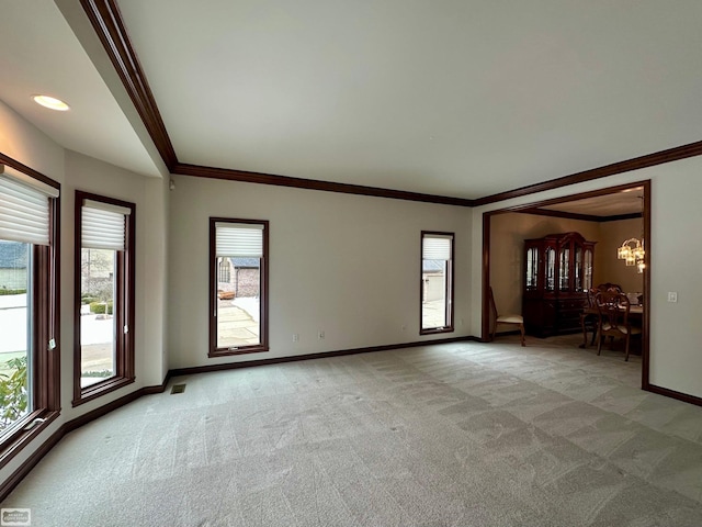 empty room with baseboards, ornamental molding, and light colored carpet