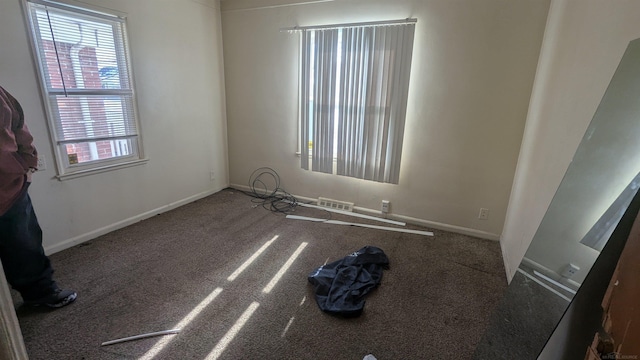 spare room with carpet flooring, visible vents, and baseboards