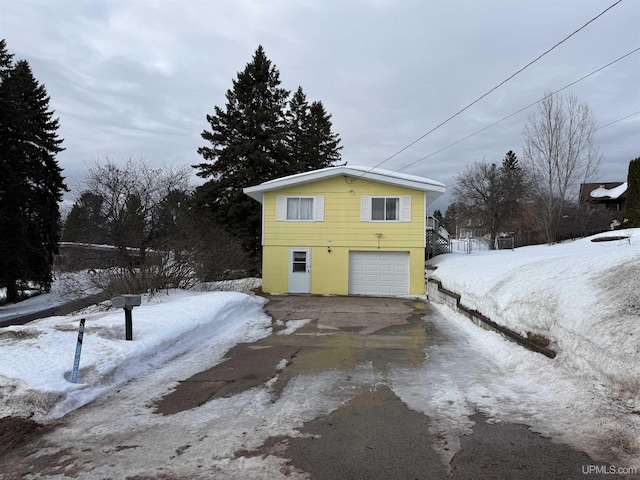 snow covered property featuring driveway and an attached garage