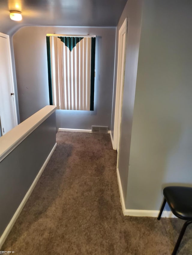 hall featuring carpet floors, visible vents, and baseboards