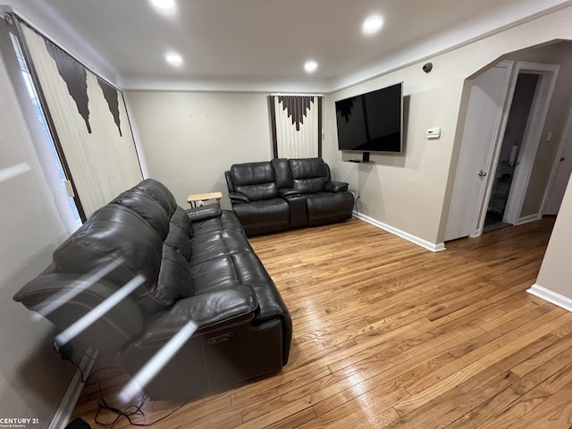 living room featuring light wood-type flooring, arched walkways, baseboards, and recessed lighting