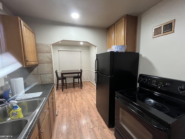 kitchen featuring visible vents, brown cabinetry, black range with electric stovetop, light wood-type flooring, and a sink