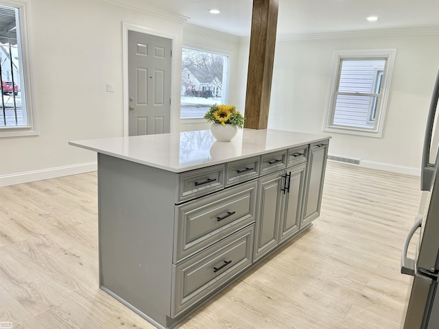 kitchen with light countertops, ornamental molding, light wood-type flooring, and gray cabinets