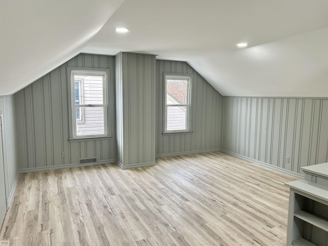 additional living space featuring lofted ceiling, visible vents, baseboards, and wood finished floors