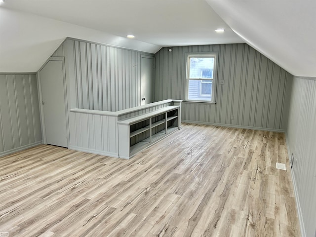 additional living space with lofted ceiling, wood finished floors, visible vents, and baseboards