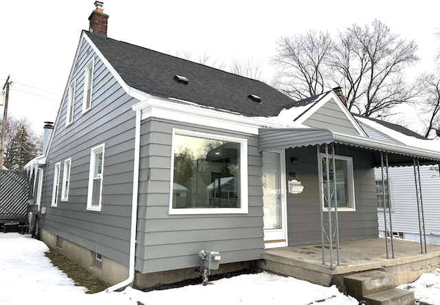 view of front of house with covered porch, a shingled roof, and a chimney