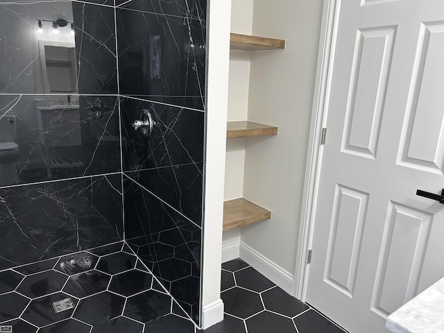 bathroom featuring a tile shower, baseboards, and tile patterned floors