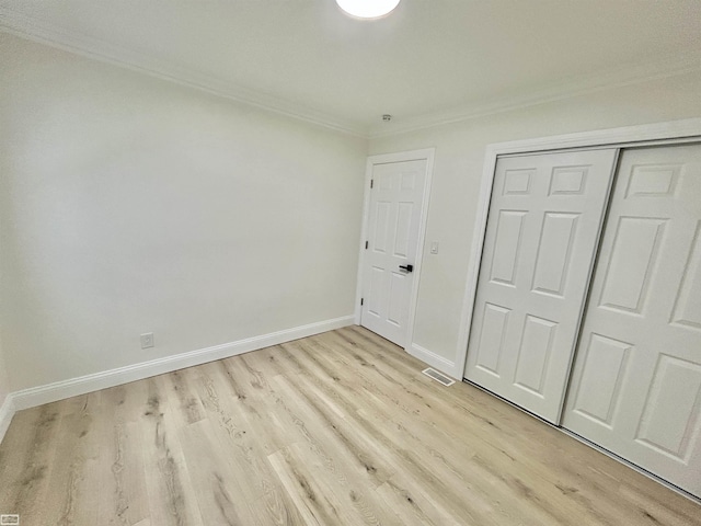 unfurnished bedroom with visible vents, baseboards, crown molding, light wood-type flooring, and a closet