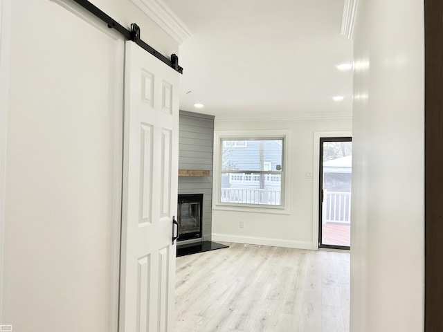 corridor with a barn door, baseboards, ornamental molding, light wood-type flooring, and recessed lighting