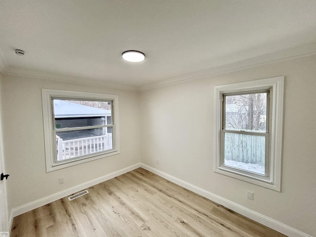 unfurnished room featuring visible vents, crown molding, light wood finished floors, and baseboards