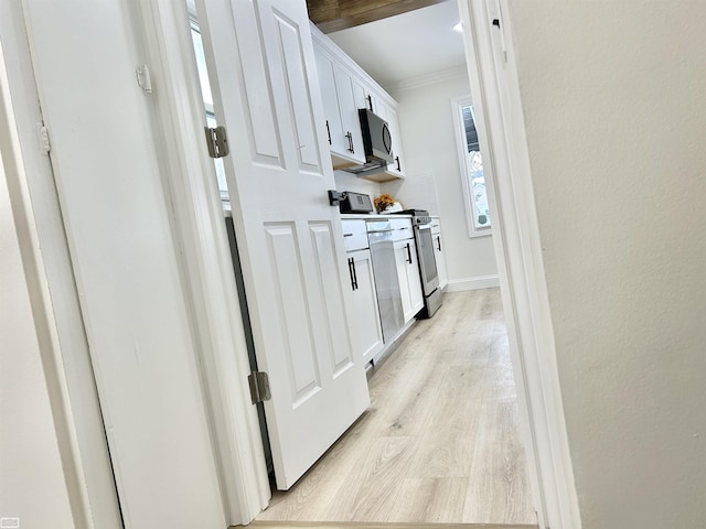 kitchen featuring baseboards, appliances with stainless steel finishes, crown molding, light wood-style floors, and white cabinetry