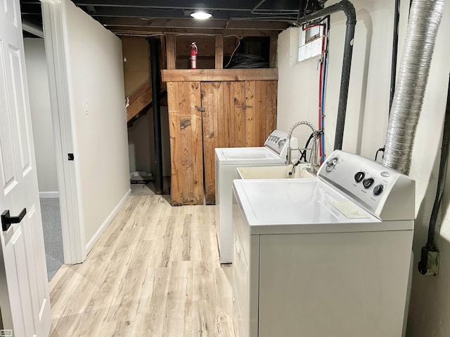 laundry room with laundry area, washing machine and dryer, light wood-style flooring, and baseboards