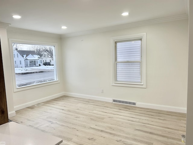 unfurnished room with baseboards, light wood-style flooring, visible vents, and crown molding