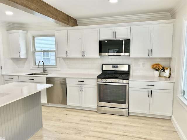 kitchen with beam ceiling, appliances with stainless steel finishes, light wood-style floors, white cabinetry, and a sink