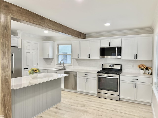 kitchen featuring white cabinets, appliances with stainless steel finishes, a sink, light countertops, and beam ceiling