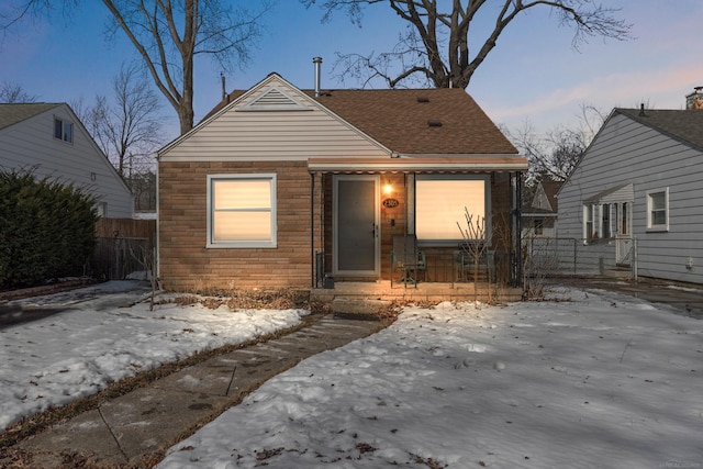 bungalow-style home featuring a shingled roof and fence