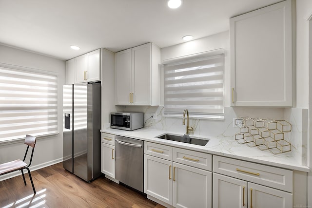 kitchen with stainless steel appliances, recessed lighting, white cabinets, a sink, and wood finished floors