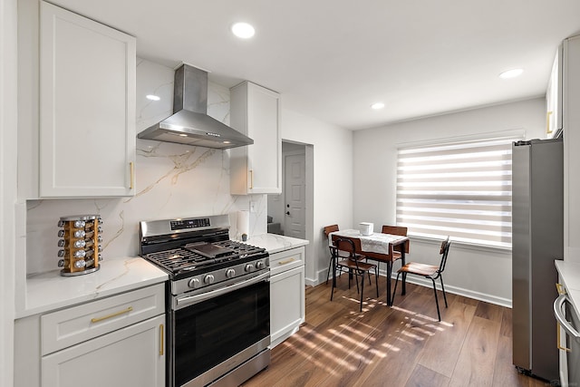 kitchen with light stone countertops, stainless steel appliances, dark wood-style flooring, decorative backsplash, and wall chimney exhaust hood