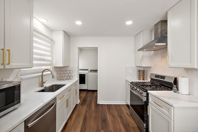 kitchen with decorative backsplash, appliances with stainless steel finishes, a sink, independent washer and dryer, and wall chimney exhaust hood