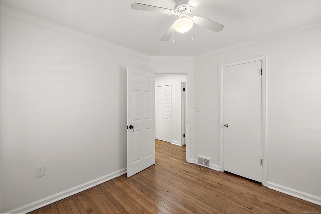 unfurnished bedroom with a ceiling fan, visible vents, baseboards, ornamental molding, and hardwood / wood-style floors