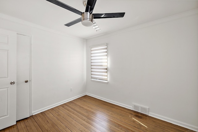 empty room featuring visible vents, hardwood / wood-style floors, ornamental molding, ceiling fan, and baseboards