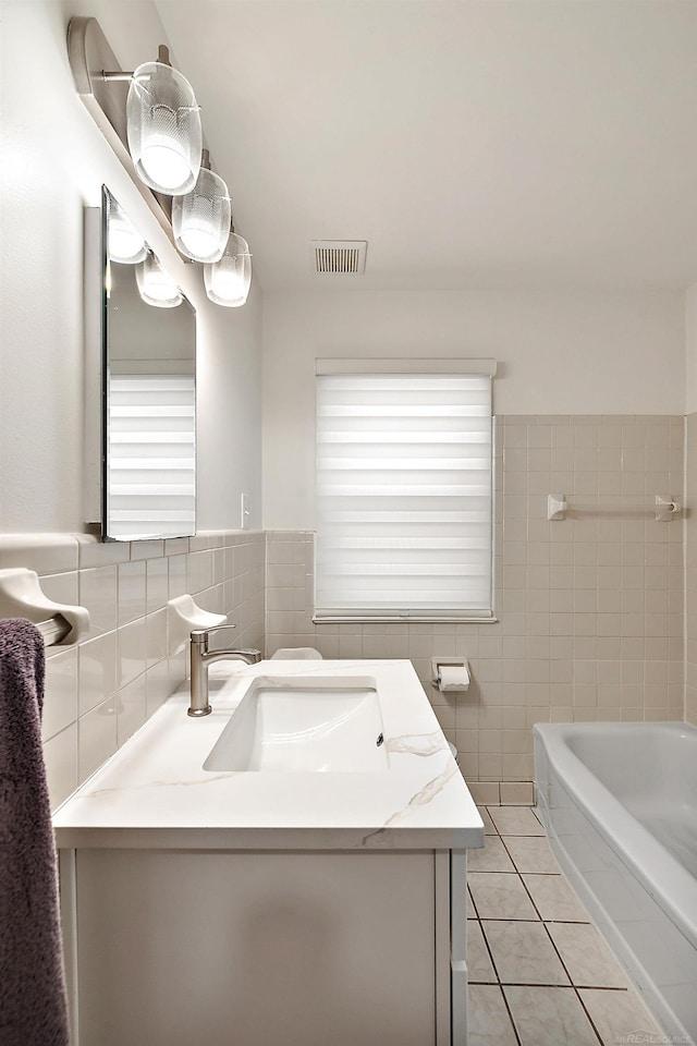 full bathroom featuring a bathtub, tile walls, visible vents, vanity, and tile patterned flooring