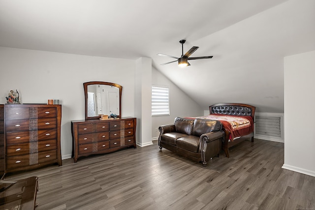 bedroom with lofted ceiling, dark wood finished floors, and baseboards