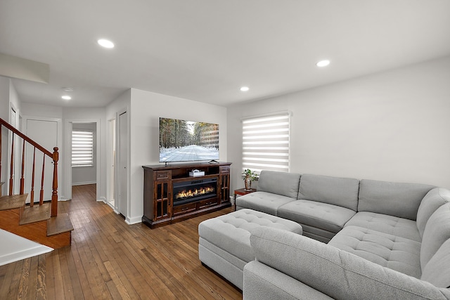 living area featuring plenty of natural light, stairway, hardwood / wood-style floors, and a glass covered fireplace