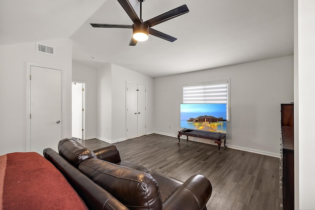 living area featuring lofted ceiling, ceiling fan, dark wood-type flooring, visible vents, and baseboards